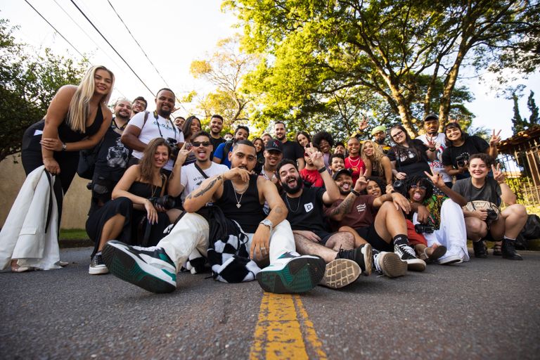 A large group of diverse adults smiling and posing outdoors on a sunny day.