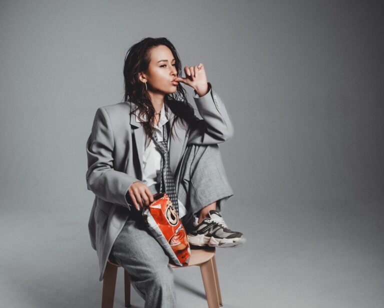 Trendy woman in gray suit enjoys snacks while seated. Perfect for lifestyle and fashion themes.