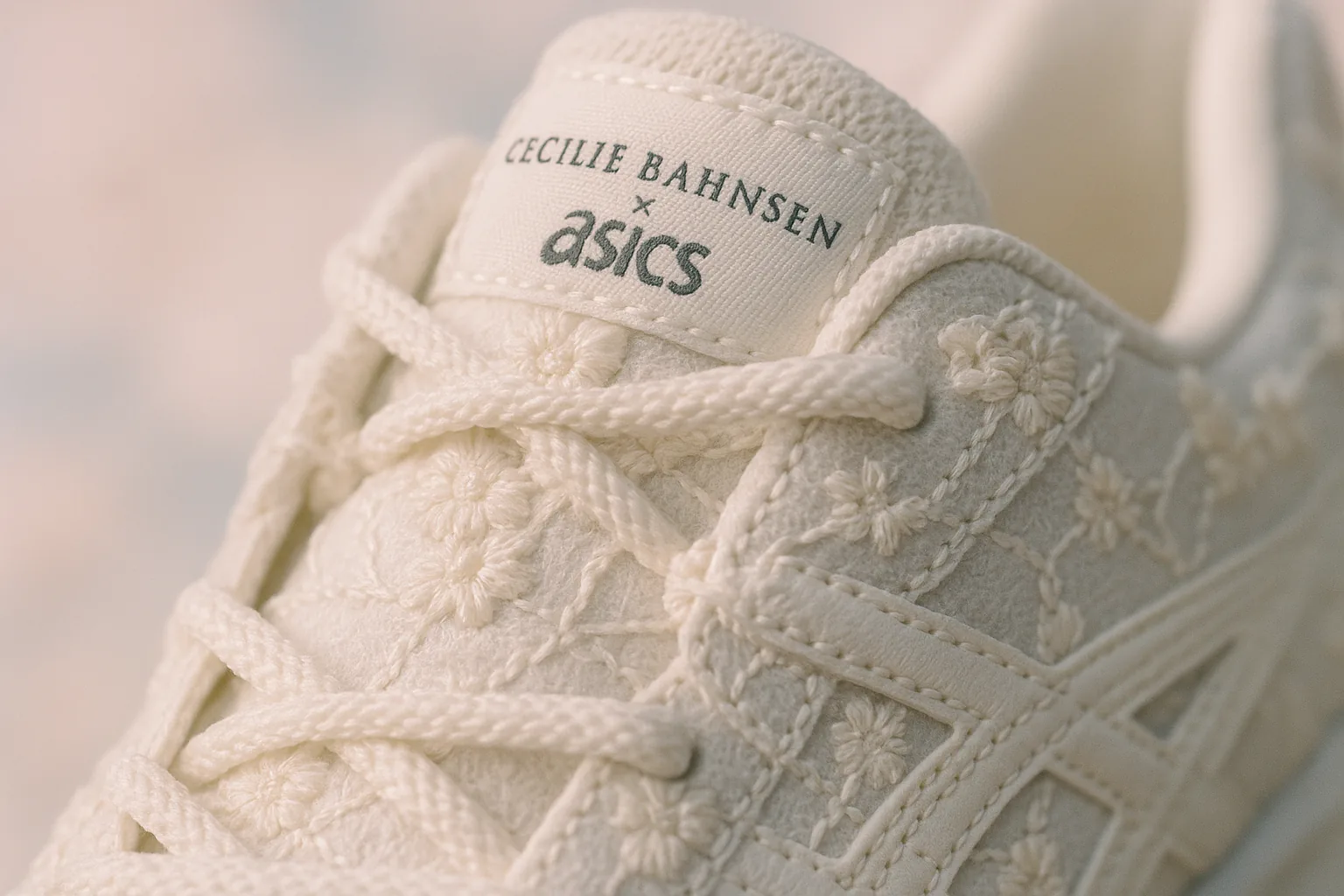 Macro shot highlighting the intricate scalloped stitching of a Cecilie Bahnsen x ASICS shoe against a blurred pastel background.